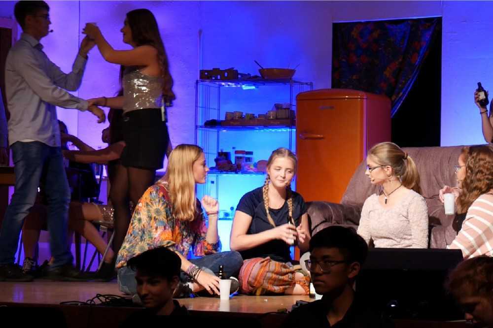 None - Vier Mädchen sitzen in einem Kreis vor einem Sofa auf einer Bühne und spielen Flaschendrehen