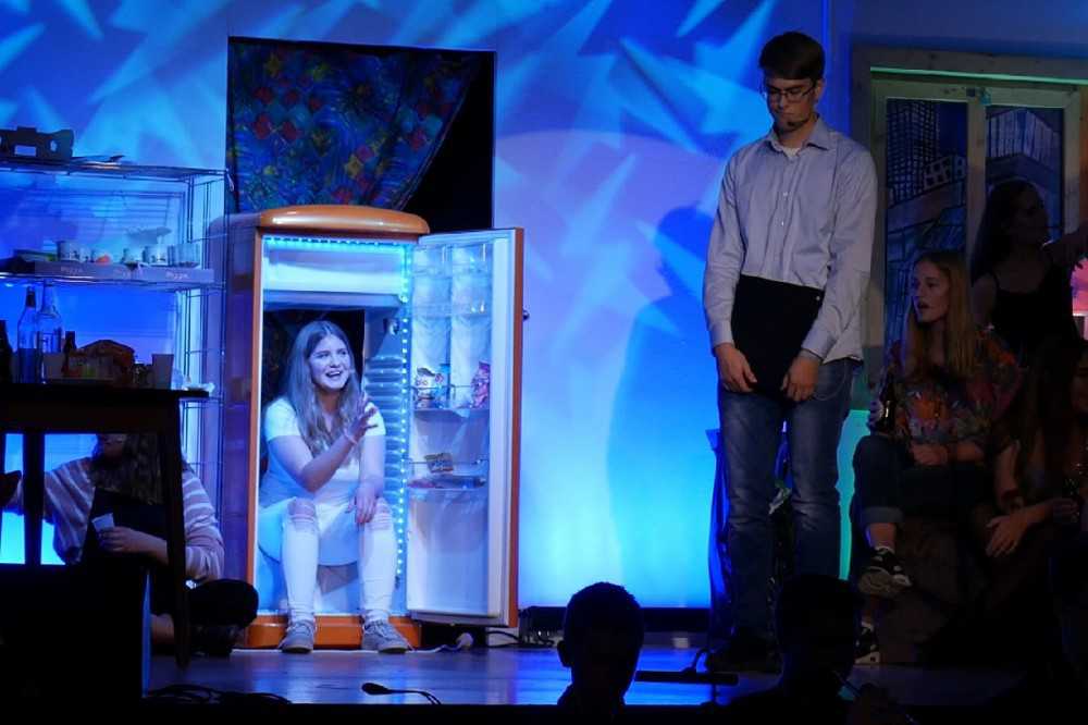 None - Ein Kühlschrank auf der Bühne ist offen und ein weiß gekleidetes Mädchen Sitz darin und ein Junge steht links neben dem Kühlschrank